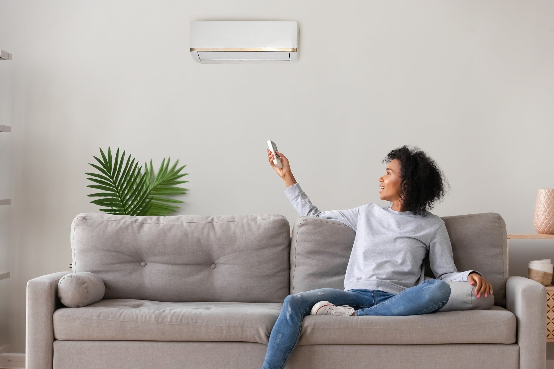 Smiling African American woman using air conditioner remote controller